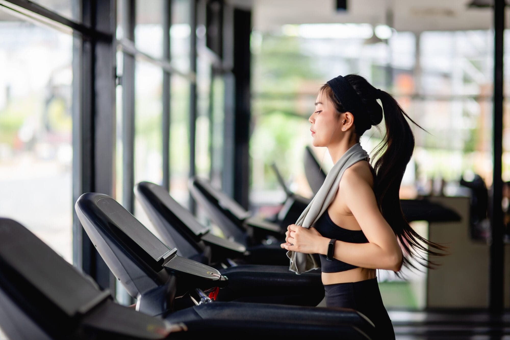 Young woman running on treadmill to workout in gym Young woman running on treadmill to workout in gym